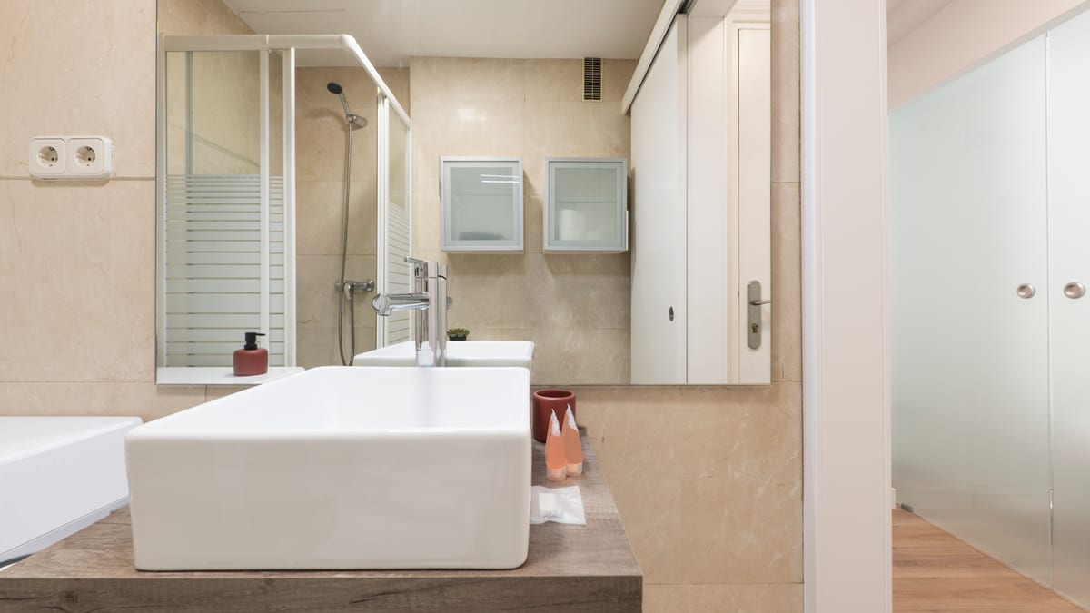 Tiled bathroom with a wood-grain vanity, large mirror and a walk-in shower.