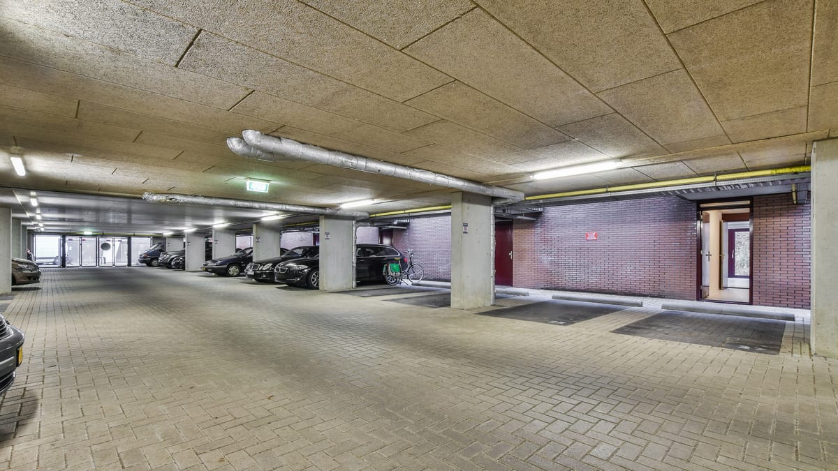 Covered resident parking area with marked bays under a wood-wool ceiling.